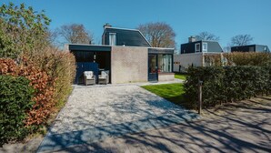 Una casa moderna con entrada de grava, un porche cubierto y un césped bien cuidado.