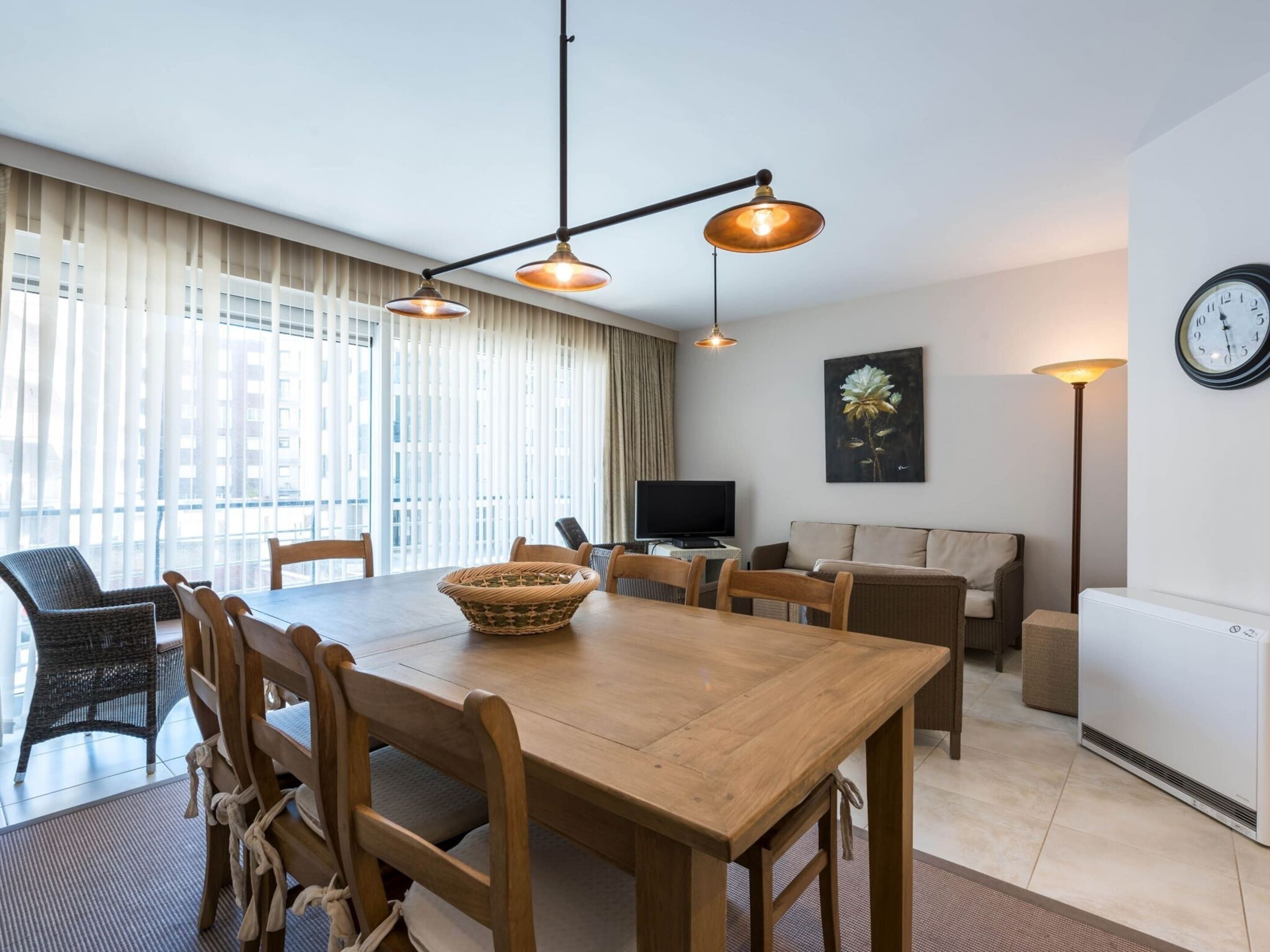 Una sala moderna con una mesa de comedor de madera, sillas, un televisor y un sofá.
