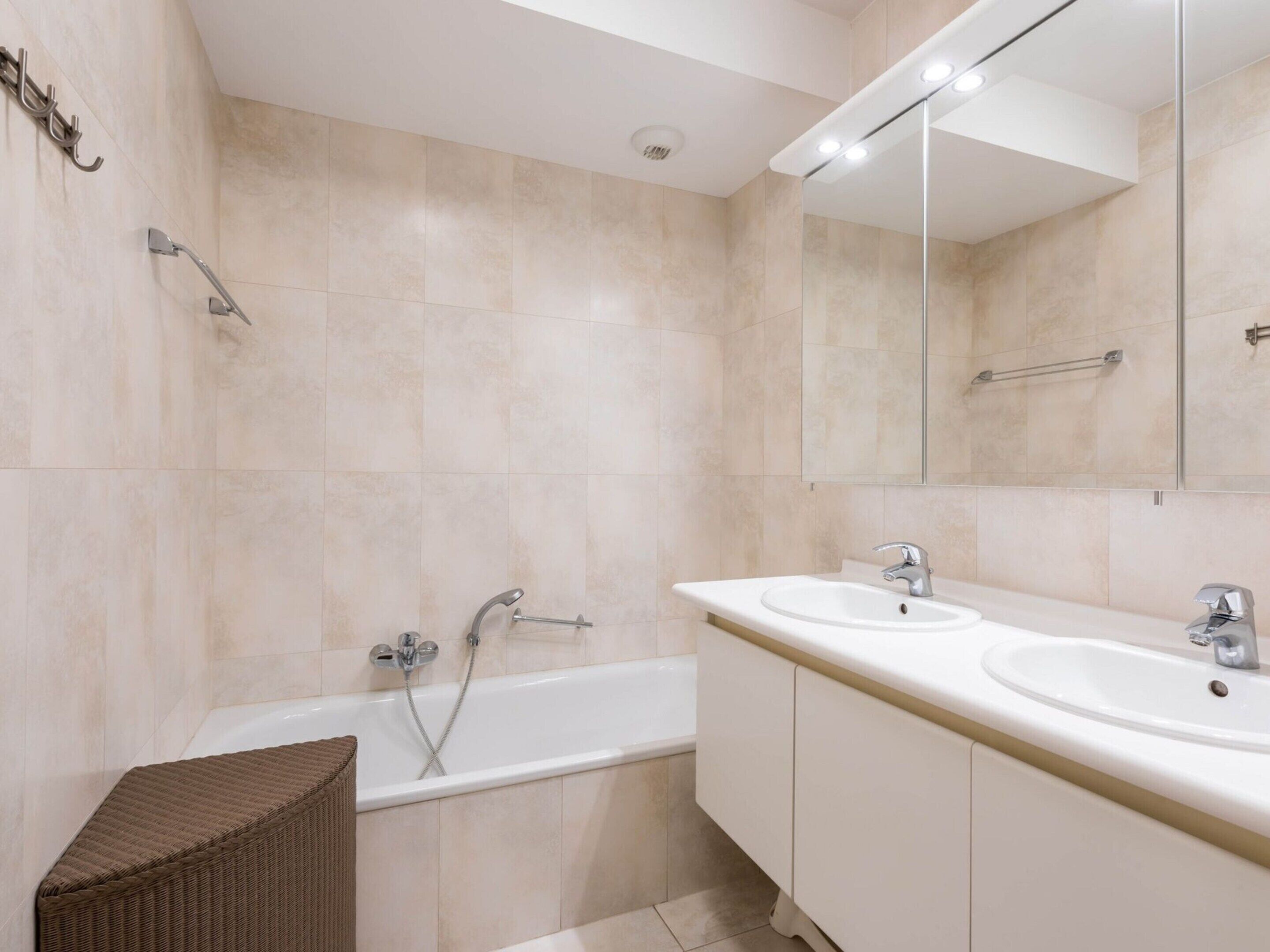 A modern bathroom with a bathtub, two sinks, and a large mirror.