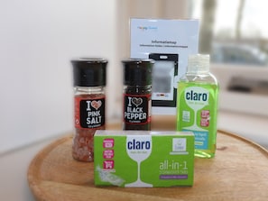 A wooden tray with a box of Claro all-in-1 dishwasher tabs, a bottle of Claro dish soap, and two salt and pepper shakers.