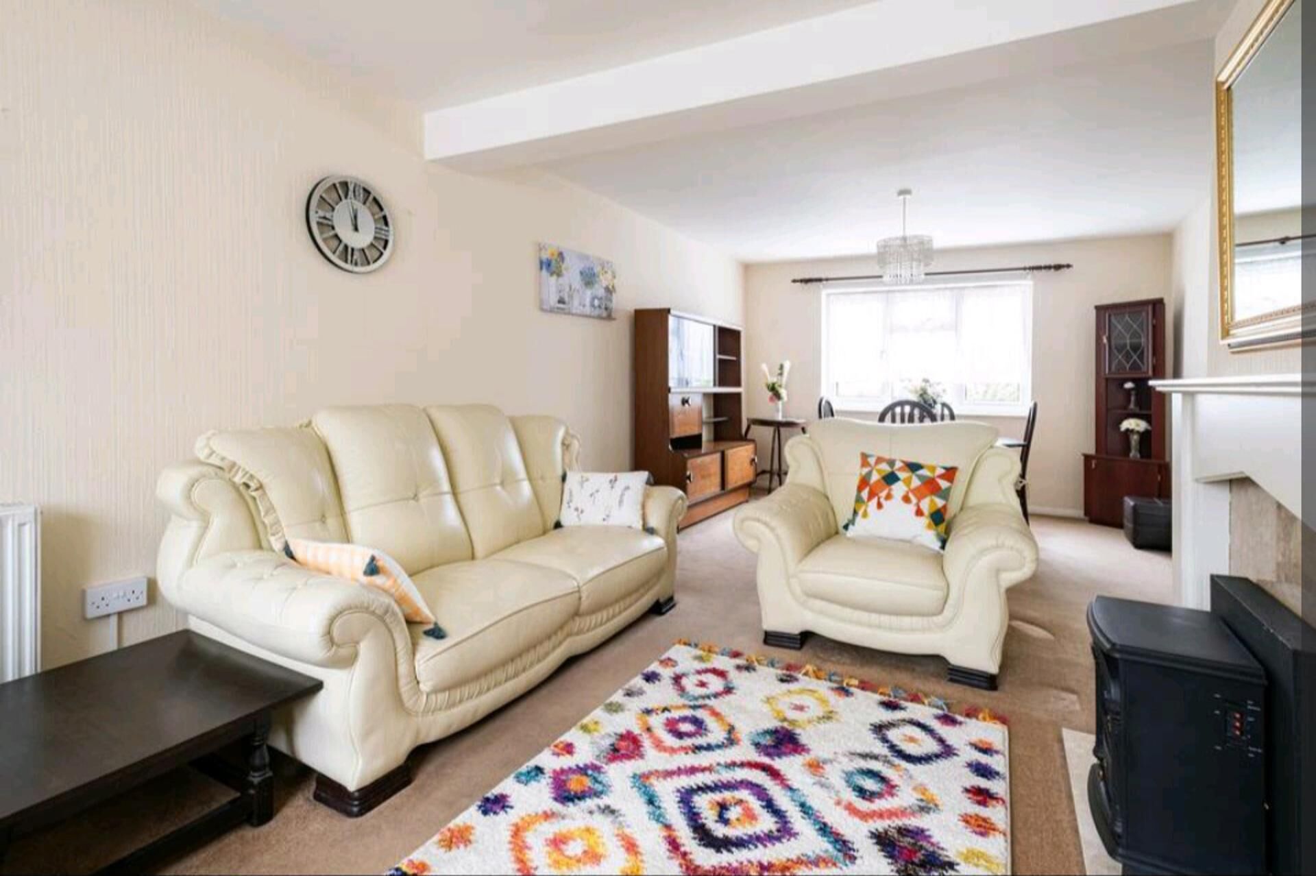 A living room with a beige sofa, a patterned rug, a wooden coffee table, and a fireplace.