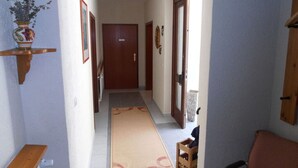 A hallway with a wooden door, a tiled floor, and a rug. - Multicultural Comfortable Holiday Residence (Kamp-Bornhofen)