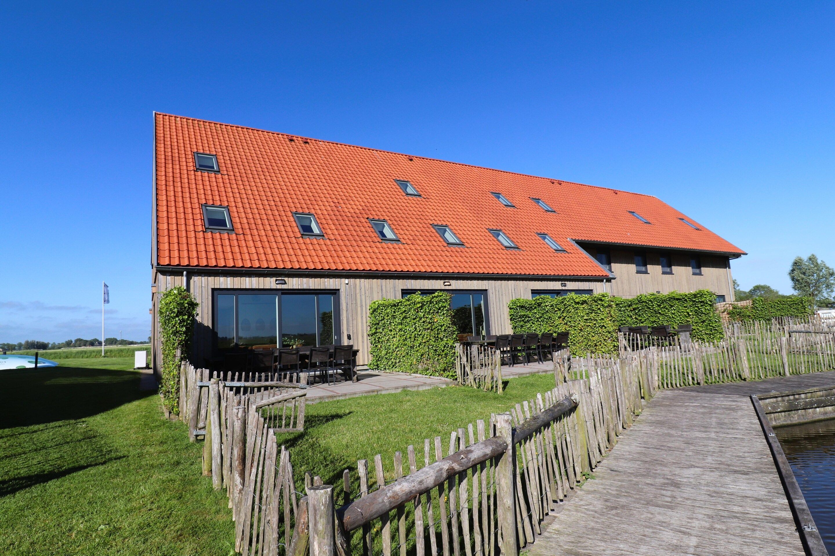 A building with a red roof, large windows, and a wooden deck.