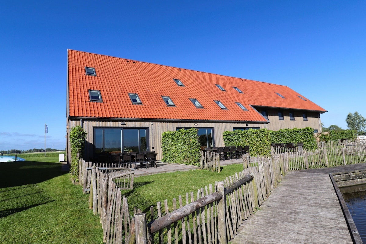 A building with a red roof, large windows, and a wooden deck.