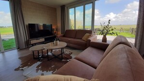 Uma sala de estar ampla, com uma grande televisão de tela plana, sofás de couro e um tapete de couro.