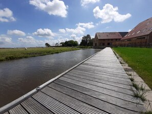 Un muelle de madera junto a un canal, con un edificio al fondo.