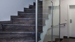 A modern staircase with glass railings and dark wooden steps. - Nice Apartment in Hopfen am See (Fuessen)