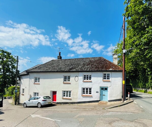 A white building with a red door, a blue door, and a chimney.