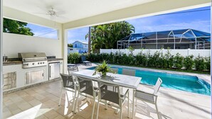 Un patio techado con piscina, cocina exterior y zona de estar.
