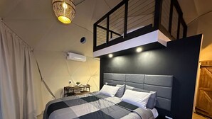 Une chambre moderne avec une couvre-lit à carreaux, une table de chevet avec une lampe et un luminaire au plafond.