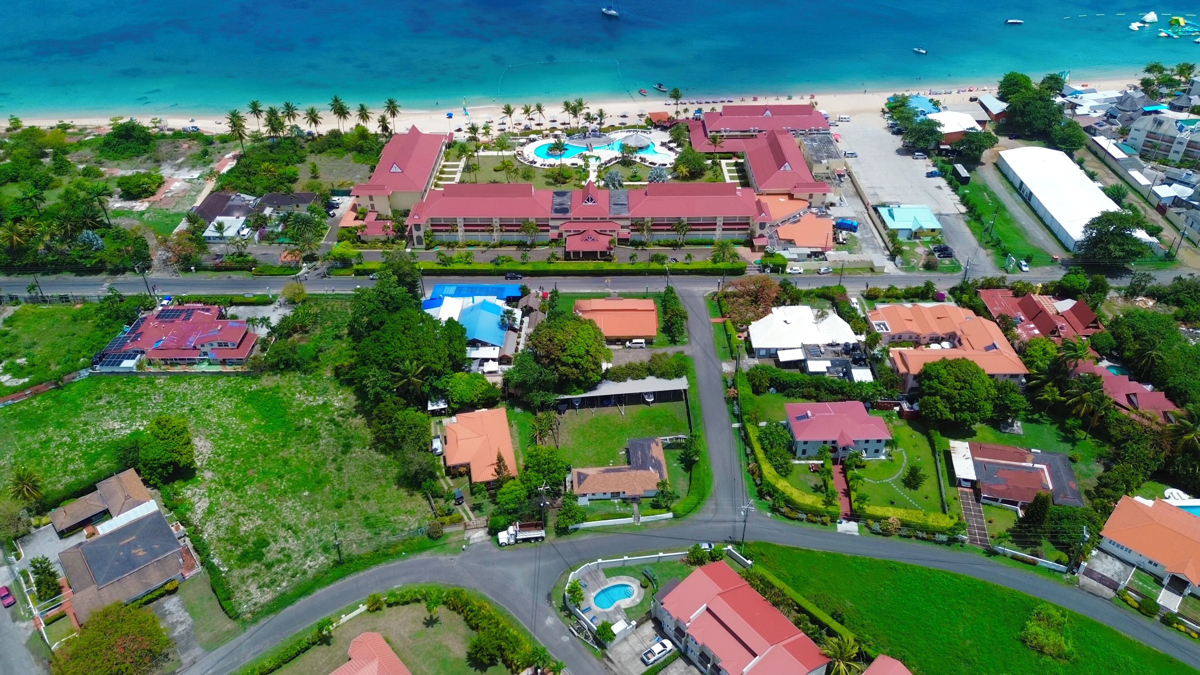 Luchtbeeld van een resort met meerdere gebouwen, een zwembad en een strand.