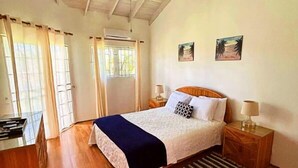 A bedroom with a wooden bed, a desk, and a chair. There are two bedside tables with lamps. - Nestled in Rodney Bay: Steps from Beaches, Shops, and Dining in St. Lucia. (Rodney Bay)