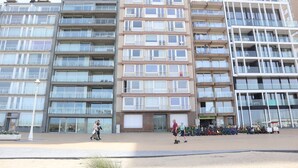 A multi-story residential building with balconies, a ground-level entrance, and a parking area with bicycles. - Apartment in Nieuwpoort With Stunning Sea View (Nieuwpoort)