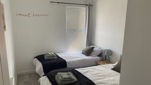 Ein Schlafzimmer mit zwei Betten, jeweils mit einer schwarz-weißen Decke, einem Nachttisch mit einer Lampe und einer kleinen Pflanze.