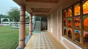 A corridor with ornate ceiling carvings, a patterned floor, and traditional windows with colorful designs. - JP GARDEN & LAWN (Mumbai)