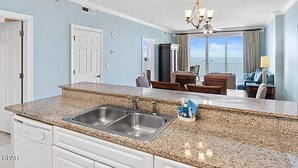 A modern kitchen with granite countertops, stainless steel appliances, and a double sink. - Emerald Isle Resort 1504 (Panama City Beach)