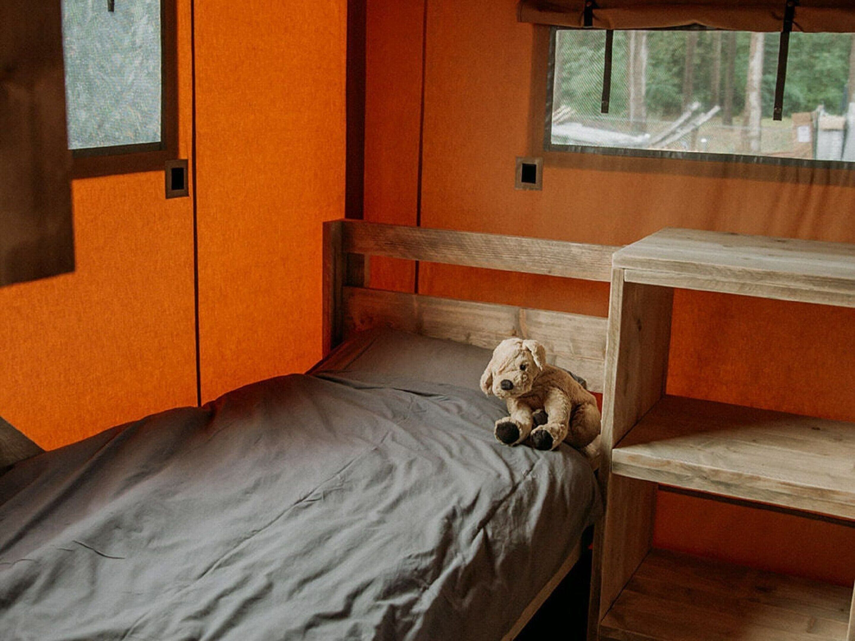 A small, single-bed room with a wooden headboard and a window.