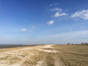 A coastal landscape with a sandy beach, a grassy field, and a small building in the distance. - Lovely Apartment in Simmerath (Wangerland)
