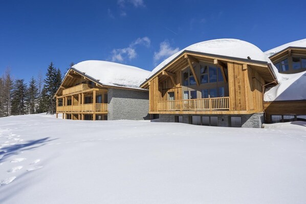 Eine schneebedeckte Lodge mit Holzbalkonage und mehreren Balkonen.
