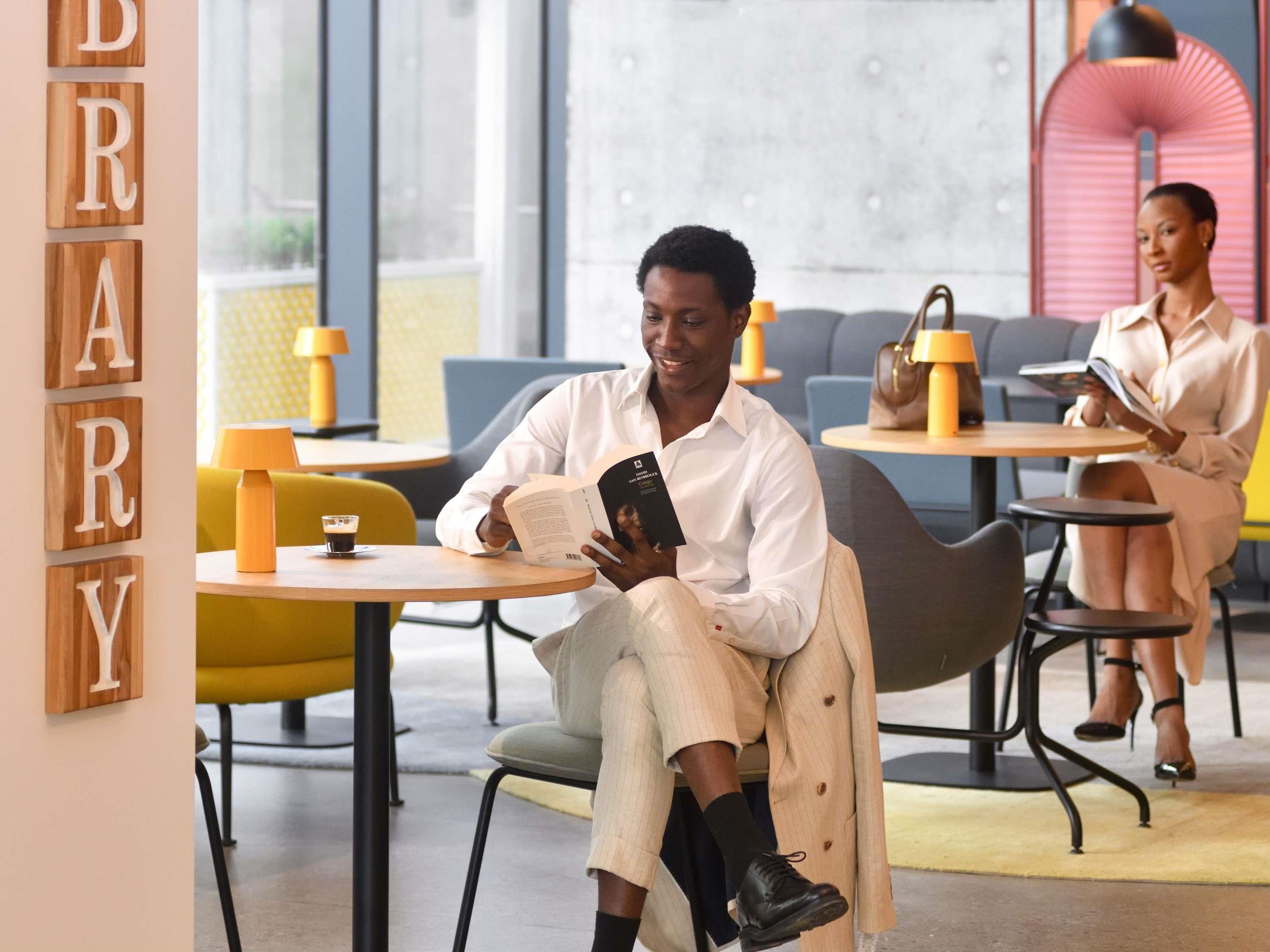 Une bibliothèque moderne, agrémentée de décorations en lettres en bois, dotée de sièges confortables et de tables avec des lampes.