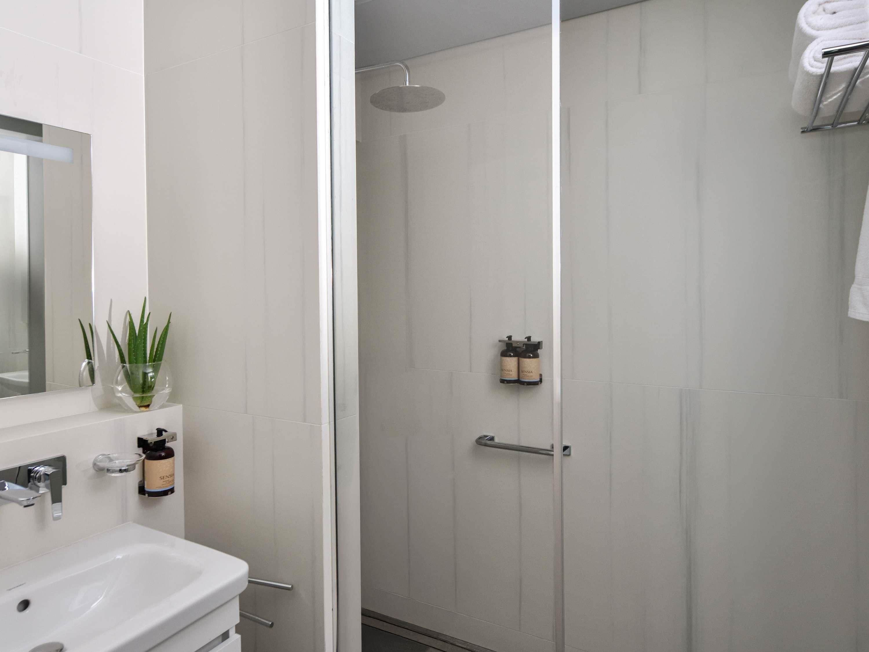 Une salle de bain moderne avec un lavabo blanc, une douche en verre et un porte-serviettes.