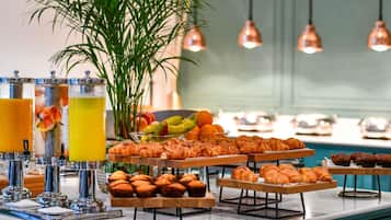 Ein reichhaltiges Frühstücksbuffet mit Gebäck, Früchten und Getränken.