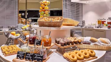 Un buffet proposant une variété de plats, notamment des fruits, des pâtisseries et des condiments.