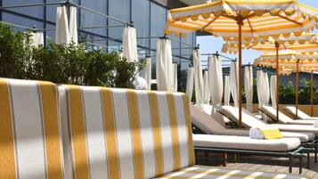 A poolside area with striped lounge chairs and umbrellas.