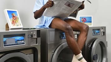 Iemand zit op een wasmachine te lezen in een krant.
