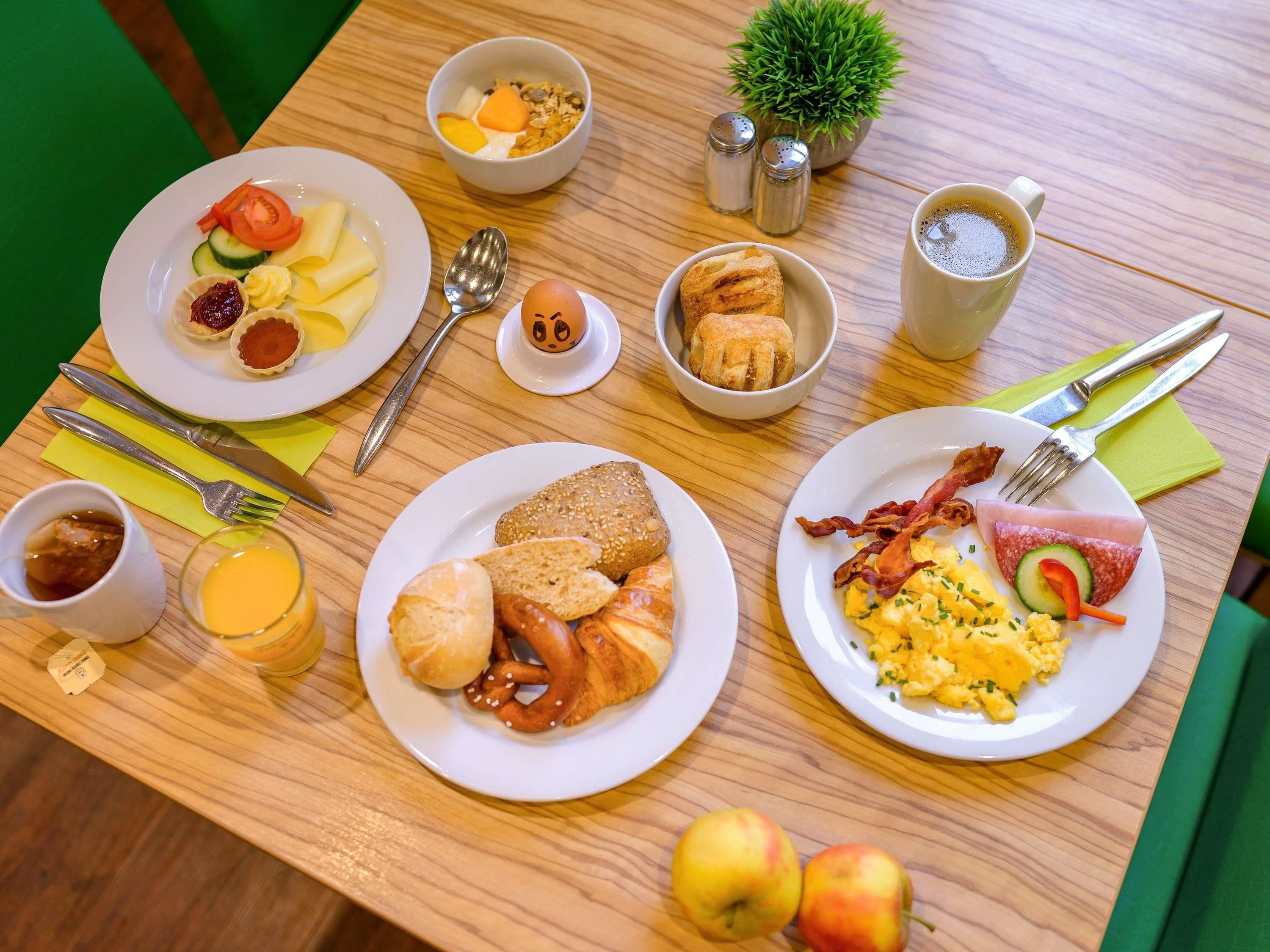 A breakfast table with plates of food, a cup of coffee, and a small plant.