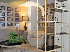 A modern living room with a sofa, a coffee table with plants, a floor lamp, and a wall with framed pictures. - Bucharest Unirii Square - Handwritten Collection (Bucharest)