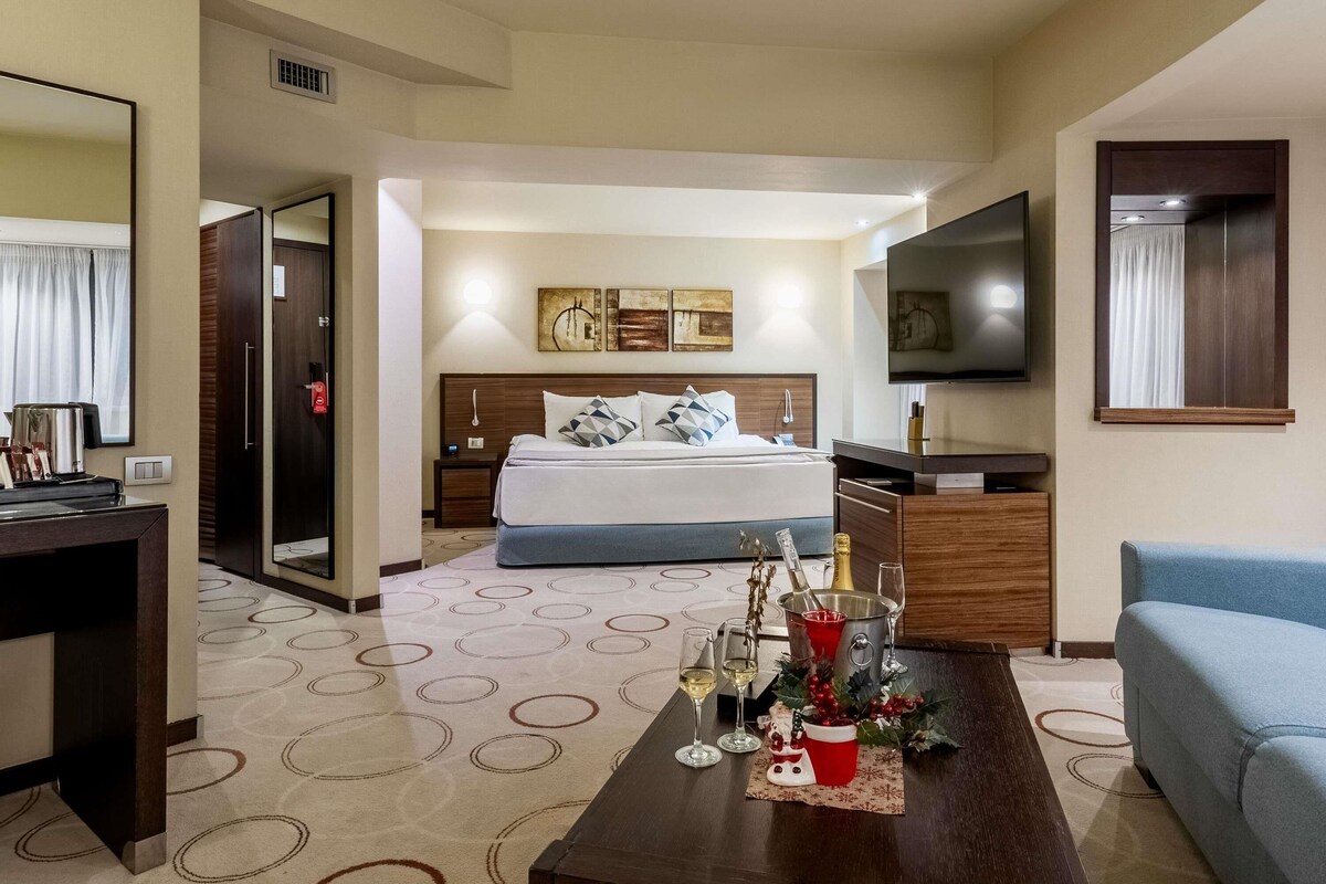 Una habitación de hotel con cama, televisión, escritorio y cafetera.