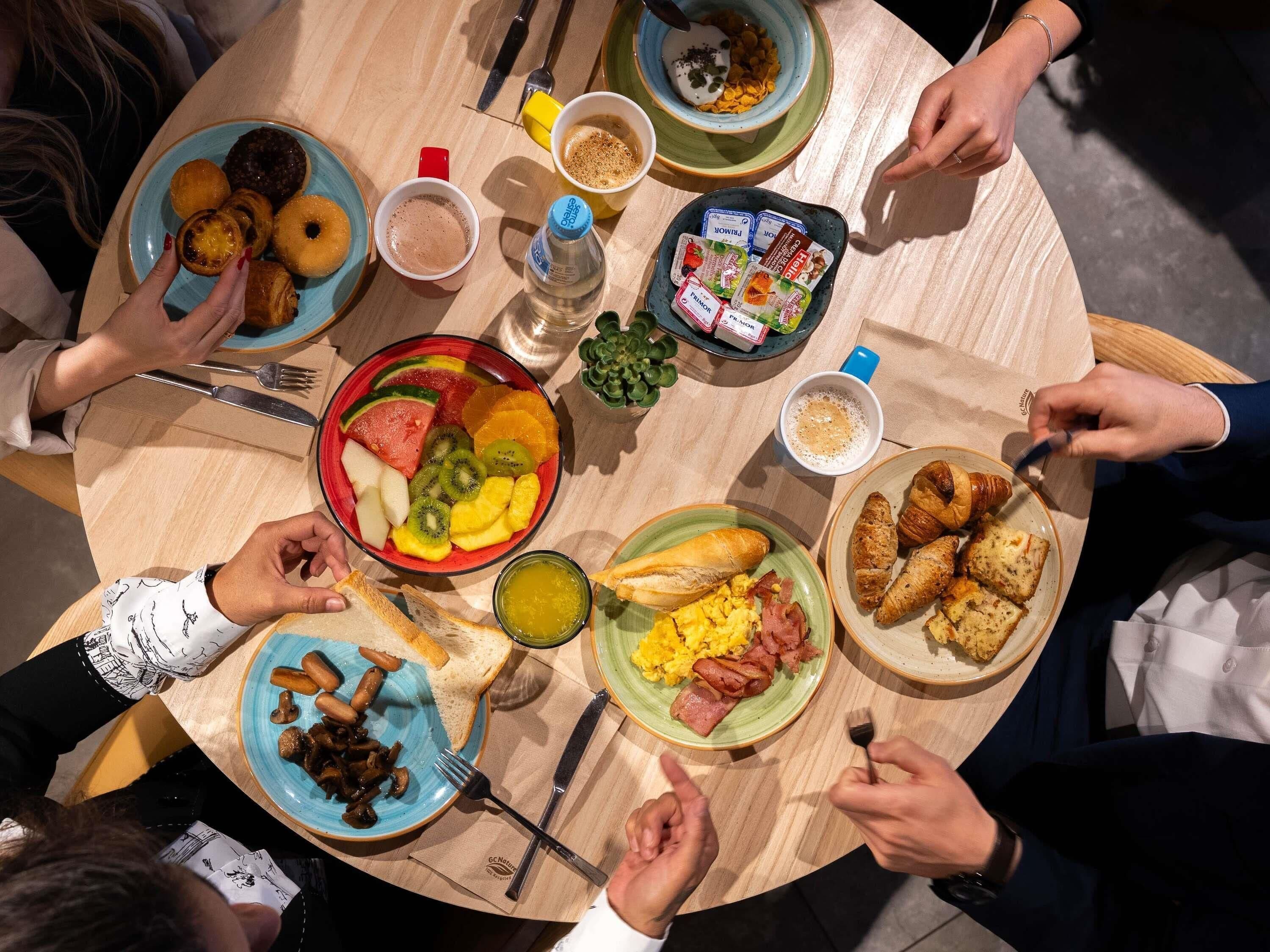 Una mesa redonda con diferentes opciones de desayuno, como frutas, bollería y salsas.