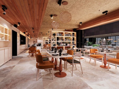 A modern interior with a long corridor, open seating area, and a large bookshelf.. ibis Styles Lisboa Aeroporto