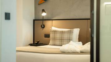 Ein modernes Hotelzimmer mit Bett, Nachttischlampe, Telefon und Wanddeko.