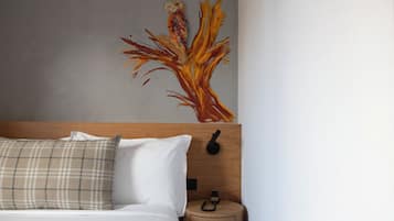Una camera da letto con un letto, un comodino, un telefono montato a parete e un quadro raffigurante un albero.