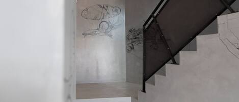 A modern staircase with a metal handrail and a wall mural.