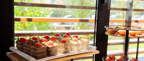 A buffet table with various food items, including sandwiches and pastries, arranged on a wooden stand.