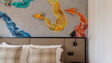 Ein Schlafzimmer mit einem Bett, Kissen und einer Wand mit farbigem abstrakten Kunstwerk.
