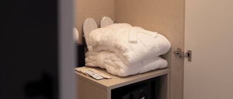 A bathroom with a towel rack holding white towels, a mirror, and a control panel below.