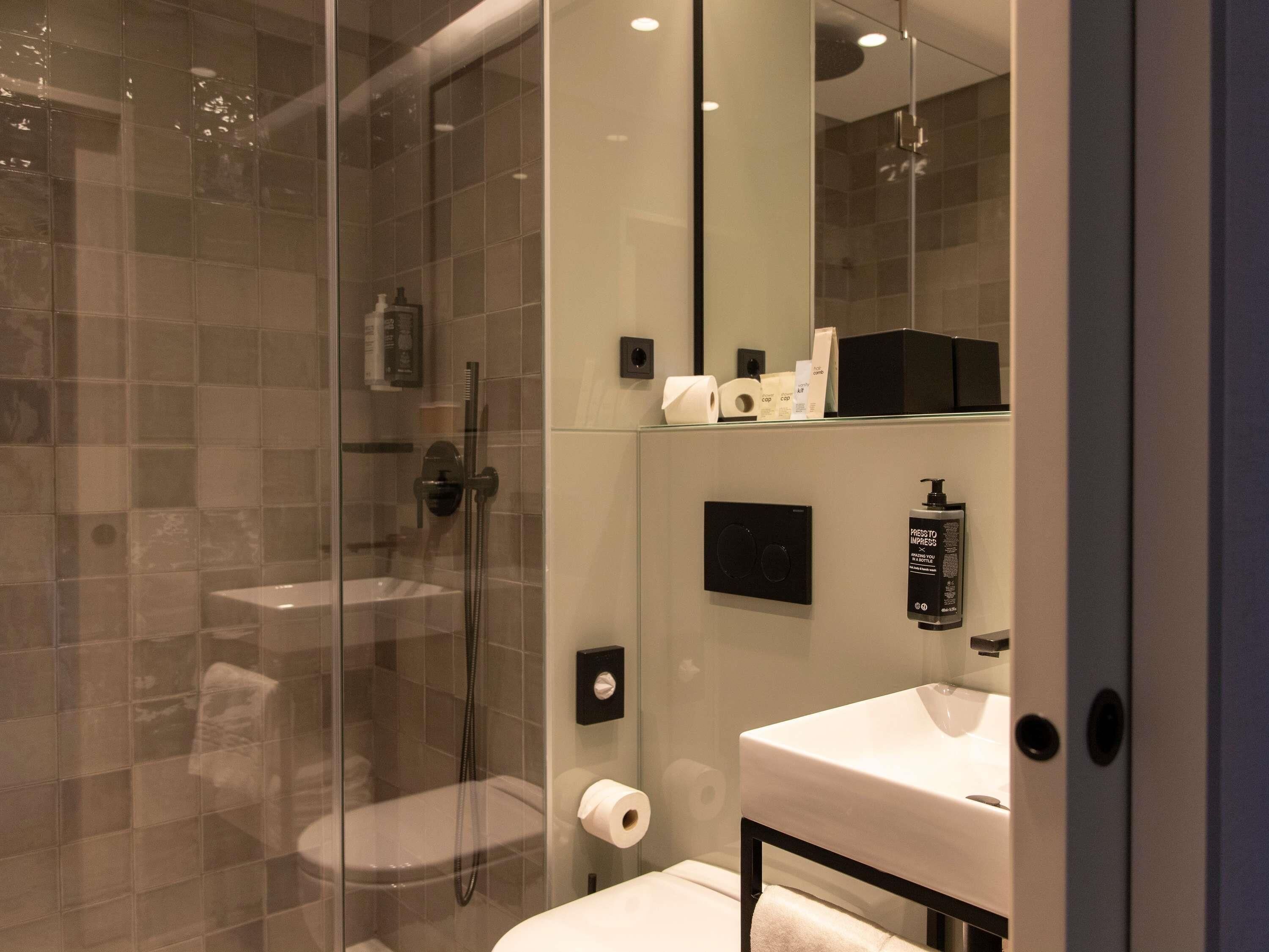 Une salle de bain moderne avec une douche à parois de verre, un lavabo blanc et un miroir.