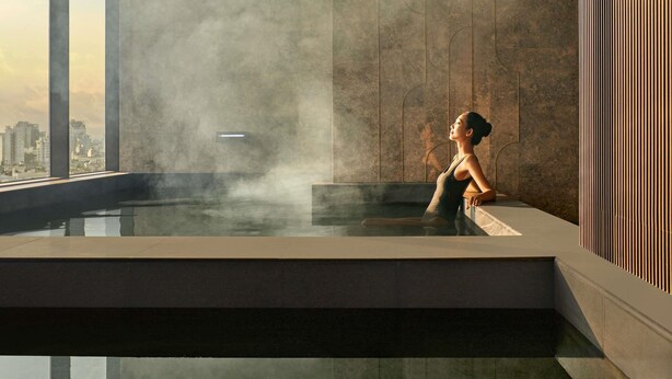 A modern indoor pool with a city view, steam rising, and a person relaxing. - Pullman Hai Phong Grand Hotel (Hai Phong)