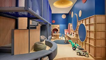 A children's play area with a slide, bean bags, and toy vehicles.