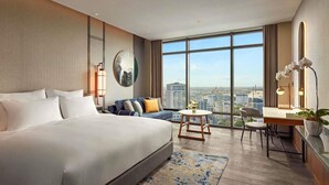 A modern hotel room with a large bed, a sofa, a desk, and a view of the city. - Pullman Hai Phong Grand Hotel (Hai Phong)