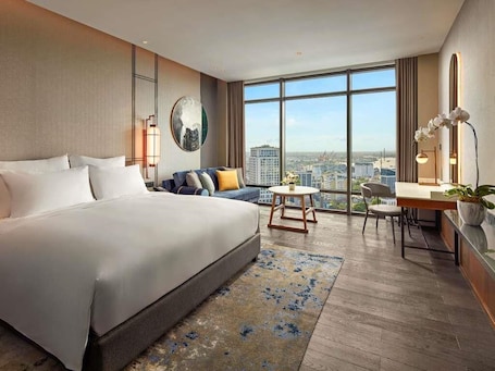 Una camera d'albergo moderna con un letto grande, un divano, una scrivania e vista sulla città.. Pullman Hai Phong Grand Hotel
