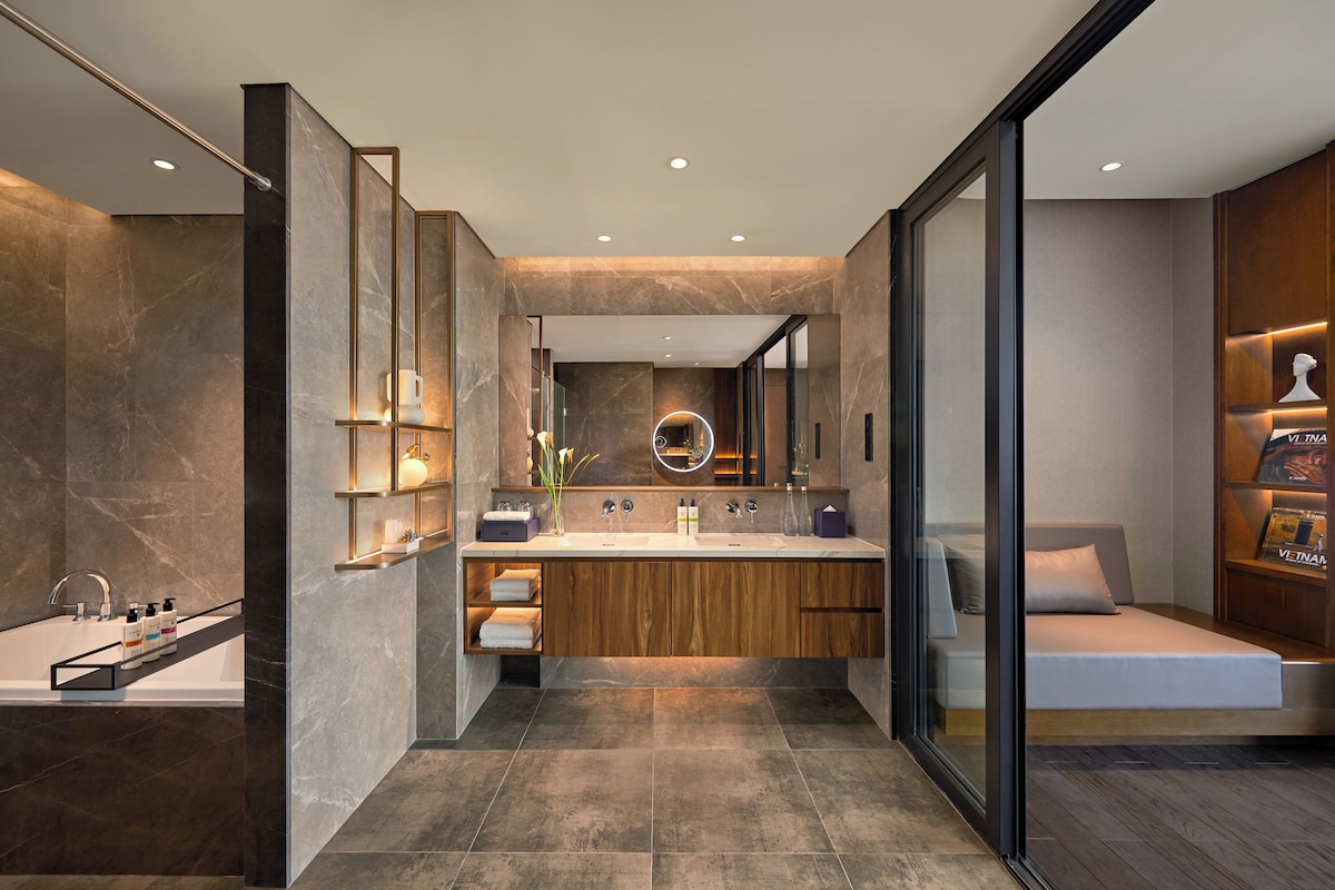 A modern bathroom with a large mirror, dual sinks, and a built-in bench.