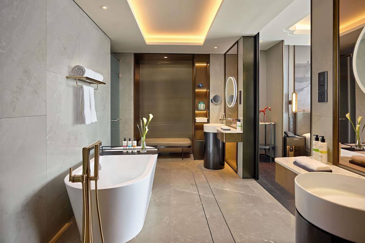 A modern bathroom with a freestanding bathtub, a vanity with a mirror, and a shower area.