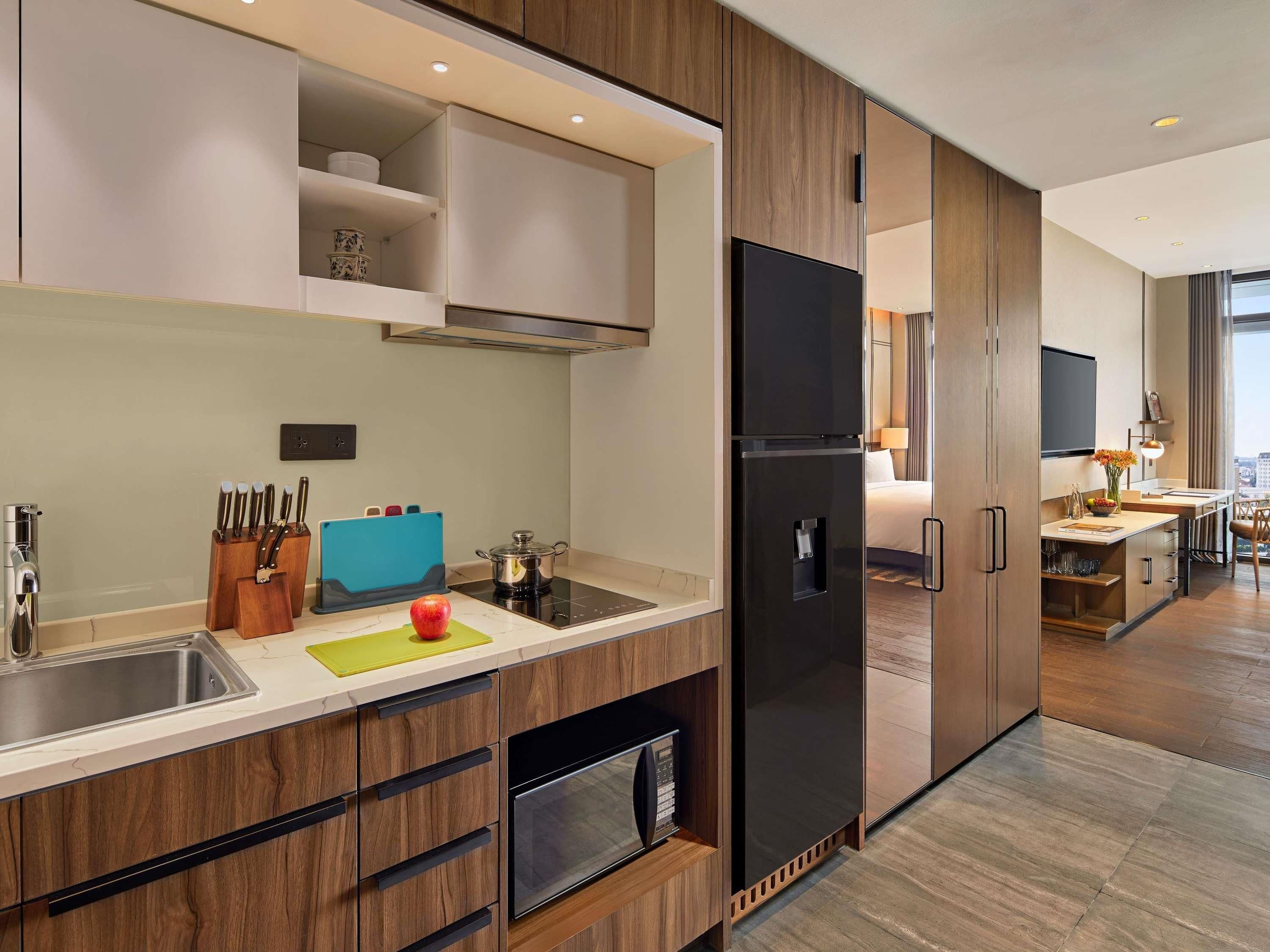 A modern kitchen with a built-in refrigerator, a sink, and a stove. There is a dining area with a table and chairs visible in the background.