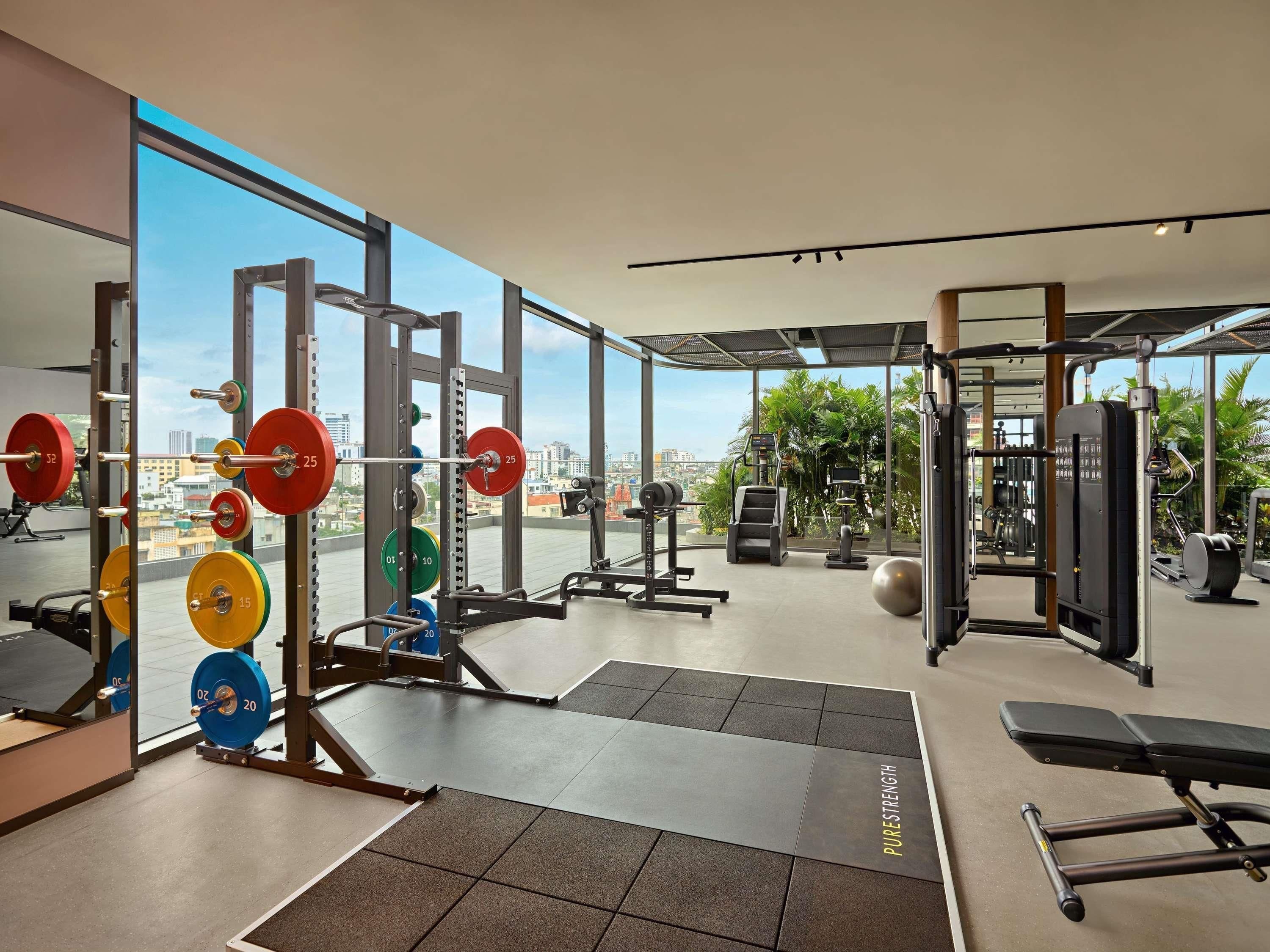 A gym with weightlifting equipment, a treadmill, and a bench.