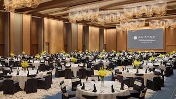A large banquet hall with round tables, black and white tablecloths, and chandeliers.